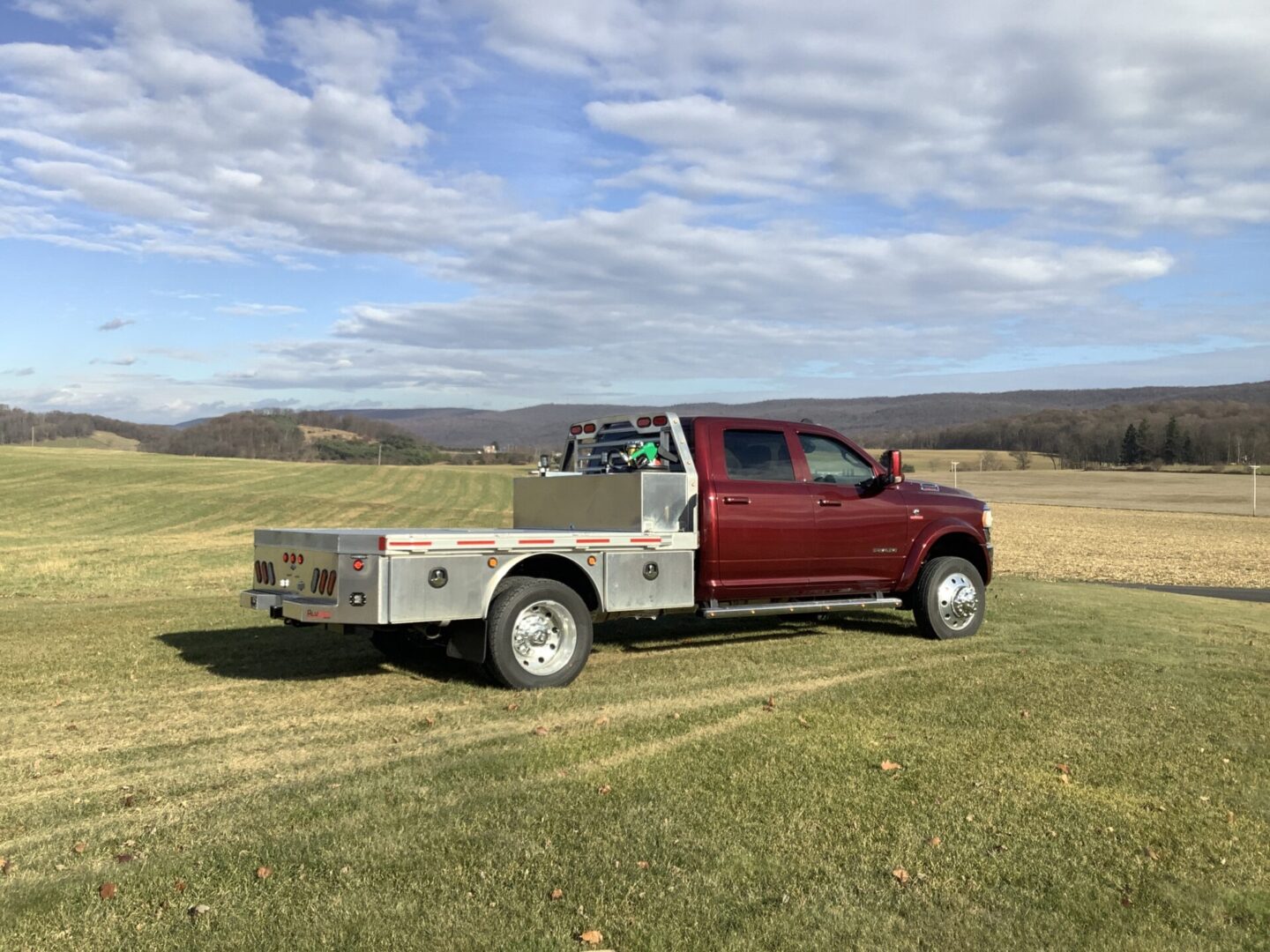 A flatbed truck parked on a grassy field with clear skies in the background.