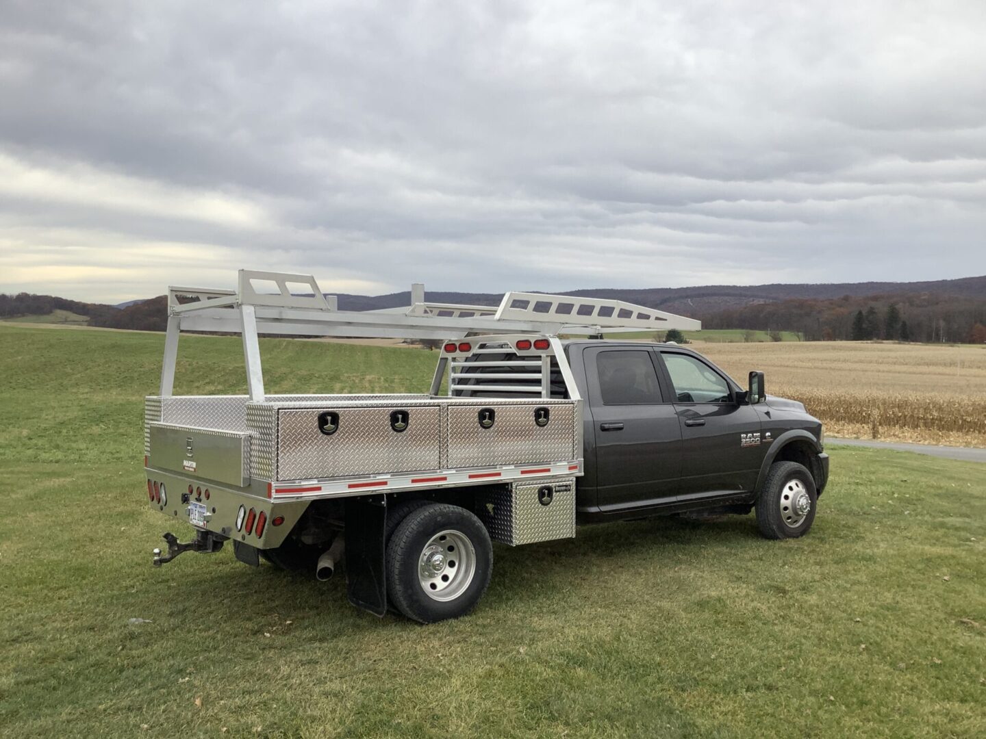 A truck with a rack standing in front of a crop field
